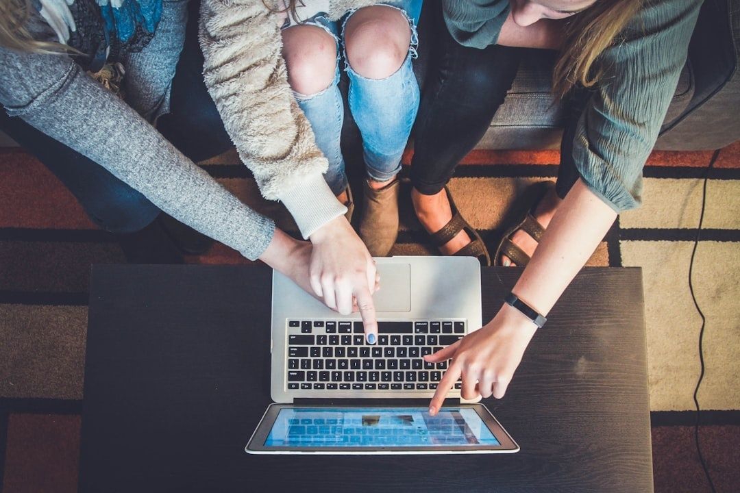Drei Personen arbeiten gemeinsam an Laptop und Tablet