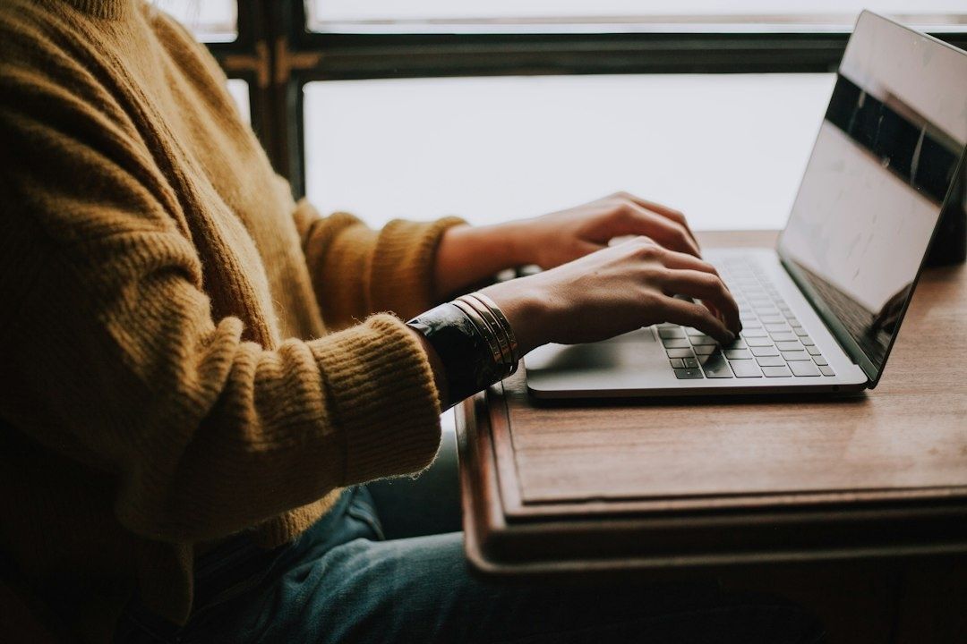 Person tippt an einem Laptop an einem Schreibtisch