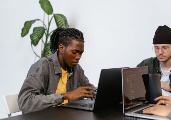 Zwei Redaktionsmitglieder arbeiten gemeinsam an Laptops