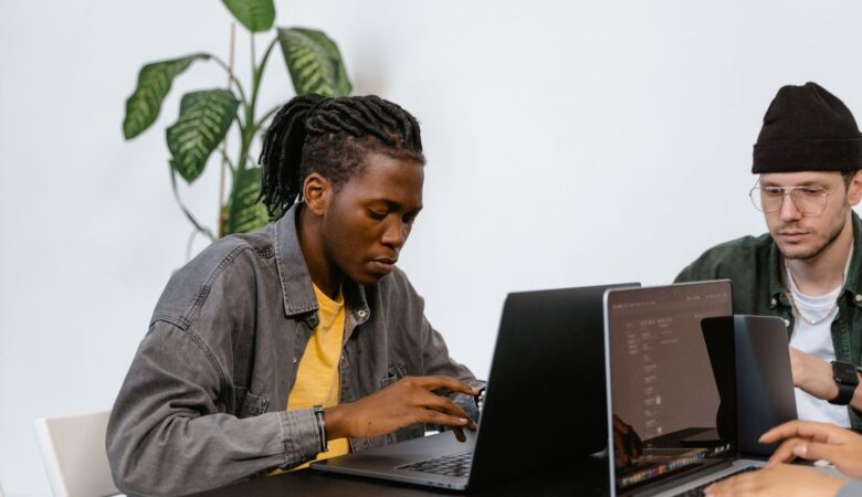 Zwei Redaktionsmitglieder arbeiten gemeinsam an Laptops